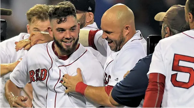  ?? STAFF PHOTO BY CHRISTOPHE­R EVANS ?? MAN OF THE (LATE) HOUR: Blake Swihart (left) is mobbed by teammates after hitting a walkoff double in the 13th inning that drove in Eduardo Nunez and helped the Red Sox defeat the Philadelph­ia Phillies, 2-1, last night at Fenway Park. The Sox stretched...