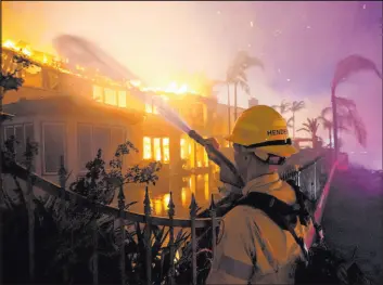  ?? Marcio J. Sanchez The Associated Press ?? A firefighte­r works on a structure burning during a wildfire on Wednesday in Laguna Niguel, Calif. No injuries were reported, but at least 20 homes were burned.