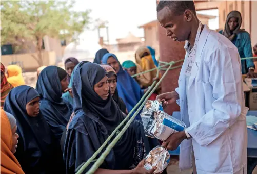  ?? During A Food Distributi­on ORGANISED By THE World Food Program In THE VILLAGE of ADLALE, ETHIOPIA. — afp file ?? A health worker delivers nutrition packs to internally displaced women