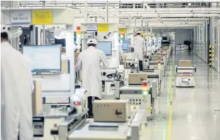  ?? /Bloomberg ?? Machines: A robot, right, passes employees working on a mobile phone assembly line at a Huawei plant in Dongguan, China.