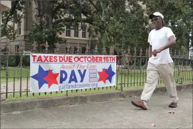  ?? The Sentinel-Record/Richard Rasmussen ?? TAX DEADLINE: Terry Harris walks past a sign in front of the Garland County Court House Friday reminding residents that real and personal property taxes are due Thursday.