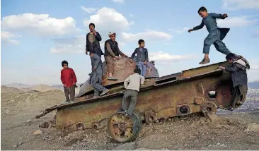  ?? [AP PHOTO] ?? Afghan children play on the remains of a Soviet tank on a hilltop on the the outskirts of Kabul earlier this month.