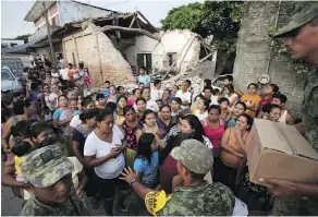  ?? REBECCA BLACKWELL/THE ASSOCIATED PRESS ?? Soldiers try to organize a crowd as they hand out rations in quake-ravaged Juchitan on Sept. 9.