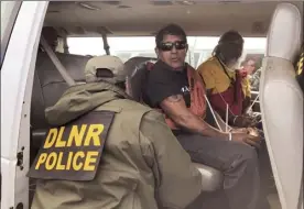  ?? Honolulu Star-Advertiser photo via AP ?? Officers from the Hawaii Department of Land and Natural Resources arrest protesters, many of them elderly, who were blocking a road to prevent constructi­on of a giant telescope on Mauna Kea on Wednesday. Police were taking away about 30 elders, who were prepared to be arrested. Protest leader Kealoha Pisciotta said hundreds of protesters moved aside to allow the elders to be taken away.