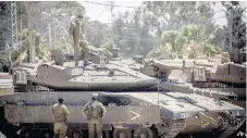  ??  ?? Soldados pemanecen frente a tanques israelíes dentro de una base militar cerca de la barrera con Gaza, donde el martes hubo fuertes enfrentami­entos.