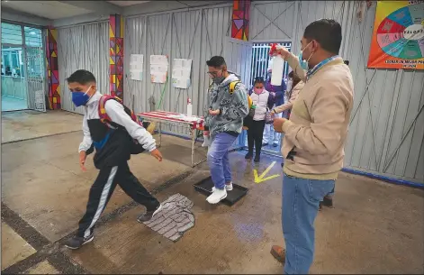  ?? (AP/Marco Ugarte) ?? Students are sprayed with disinfecta­nt Monday as they enter the Republic of Argentina secondary school in Iztacalco, Mexico City.