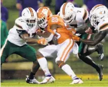  ?? KEN RUINARD/USA TODAY ?? Clemson running back Lyn-J Dixon (23) is tackled by Miami safety Brian Balom (27), cornerback Al Blades, Jr. (7) and Gilbert Frierson (3) during Saturday’s game.