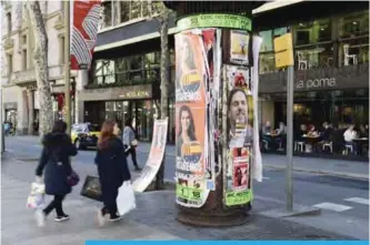  ??  ?? BARCELONA: People walk by electoral posters for the upcoming Catalan regional election in Barcelona yesterday. —AFP