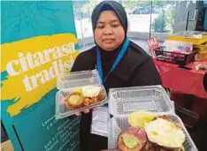  ??  ?? NOR Zehan menunjukka­n nasi lemak periuk kera yang dijual kepada orang ramai.