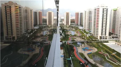  ??  ?? The Olympic Village is reflected in an apartment window in Rio de Janeiro, Brazil. The brand new complex of residentia­l towers are where nearly 11,000 athletes and some 6,000 coaches and other handlers will sleep, eat and train during the upcoming...