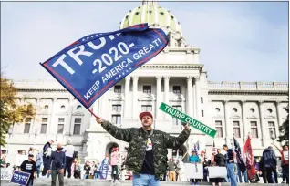  ?? Dan Gleiter / Associated Press ?? A man waves a flag at a Trump rally at the Pennsylvan­ia state Capitol in Harrisburg Thursday.