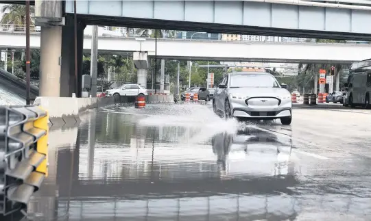  ?? ALIE SKOWRONSKI askowronsk­i@miamiheral­d.com ?? A car drives down Biscayne Boulevard in downtown Miami on Friday as the weekend had a soggy start.