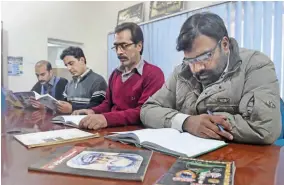  ?? — AFP ?? In this photograph, Pakistani men read Hindko language books at The Hindko Centre in Peshawar.