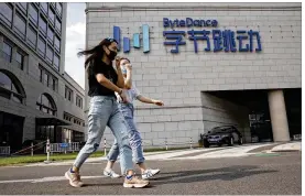  ?? NG HAN GUAN/AP ?? Women wearing masks chat as they pass by the ByteDance headquarte­rs in Beijing, China on Friday. President Donald Trump on Thursday ordered a ban on dealings with the Chinese owners of consumer apps TikTok and WeChat, although it remains unclear if he has the legal authority to actually ban the apps from the U.S.