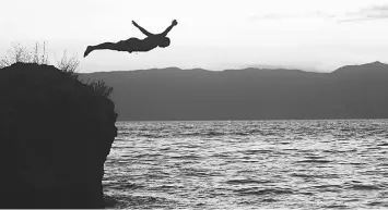  ??  ?? A man jumping from the rock in the Ohrid Lake. — AFP photos