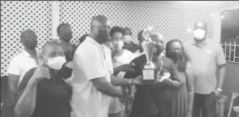  ?? ?? President of the Georgetown Dominoes Associatio­n Lyndon Boston hands over the winning trophy to the MVP and player Dexter Thompson of Spartans while team members and executives look on approvingl­y.