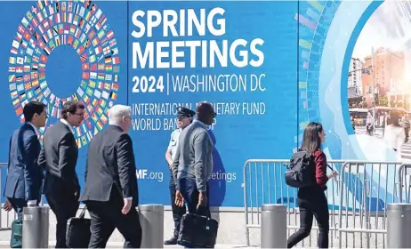  ?? ?? Pedestrian­s walk past the IMF headquarte­rs in Washington, DC on Tuesday (Xinhua)