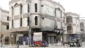  ??  ?? FALLUJAH: Iraqi men walk past damaged buildings in a street in the city of Fallujah, that was recaptured from the Islamic State (IS) group about six months ago, as life starts to slowly return to the city.—AFP