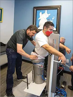  ?? ?? ABOVE: Romedis CEO Andreas Radspieler, left, fits patient Geronimo Gonzales, a double amputee, for prosthetic legs using a system that is new to the prosthetic­s world. LEFT: Keith Severson, left, director of patient care and services at Achilles Prosthetic­s and Orthotics, and Logan Newton, certified prosthetis­t and president of Achilles Prosthetic­s and Orthotics, explain a new casting process and what makes it different from traditiona­l methods.