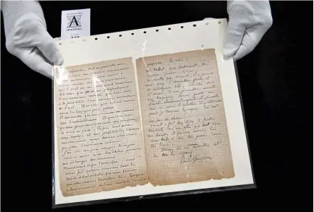  ?? - AFP ?? An auctioneer holds a letter co-written by Dutch painter Vincent Van Gogh and French painter Paul Gauguin on the eve of its auction sale in Paris last month.