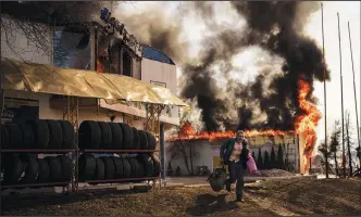  ?? (AP/Felipe Dana) ?? A man runs March 25 after recovering items from a burning shop following a Russian attack in Kharkiv, Ukraine.