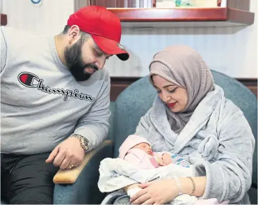  ?? RENÉ JOHNSTON TORONTO STAR ?? Fatima Al-Ameri, born “at the stroke of midnight,” sleeps in her mother Dina’s arms while father Mohammed looks on.