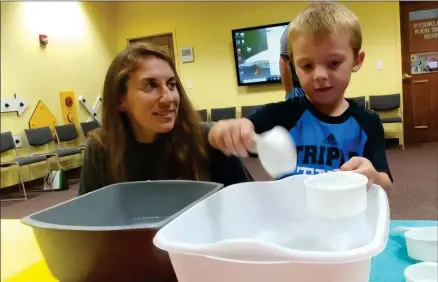  ?? ZACHARY SRNIS — THE MORNING JOURNAL ?? Avon resident Amy Fortener conducts an experiment Sept. 4 with her son, Noah, 4, at the library in North Ridgeville.