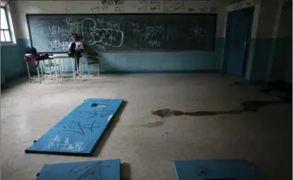  ??  ?? Above, a student sits on a teacher’s desk inside what was once a classroom, where doors lie on the floor at a public high school in Caracas, Venezuela. The social and economic chaos stalking Venezuela is ripping apart its once-enviable school system.