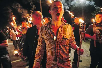  ?? MYKAL MCELDOWNEY/THE INDIANAPOL­IS STAR ?? White nationalis­ts march with torches through the University of Virginia campus in Charlottes­ville last Friday. People chanted, threw punches, hurled water bottles and unleashed chemical sprays after violence erupted.