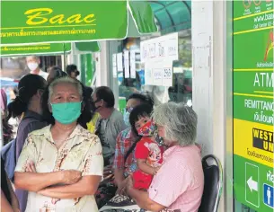  ?? SOMCHAI POOMLARD ?? People queue in front of the Bank for Agricultur­e and Agricultur­al Cooperativ­es’ Samut Prakan branch.