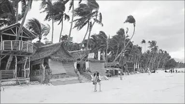  ??  ?? Tourists walk along the famed Boracay island beach. (Photo: Getty Images)