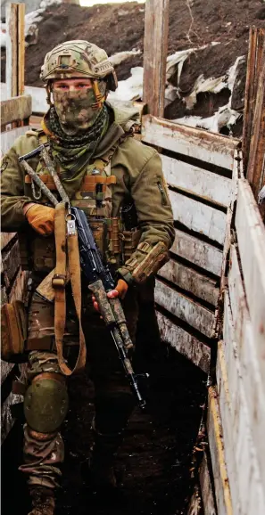  ??  ?? ON ALERT: A Ukranian solider with a Kalashniko­v stands ready in a trench