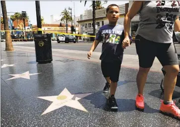  ?? Christina House Los Angeles Times ?? VISITORS WALKING on the Hollywood Walk of Fame on Hollywood Boulevard and Highland Avenue are redirected while the LAPD investigat­es a fatal police shooting near the scene that left a man dead Thursday.