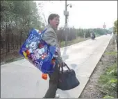  ??  ?? A person carrying a bag bearing the image of Mickey Mouse walks in Qigan Village in Chuansha in November 2009, a year and a half before the constructi­on of the Shanghai Disney Resort in the same location.