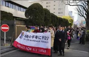  ?? (AP/Hiro Komae) ?? Plaintiffs holding a banner walk into the Tokyo district court on Thursday for the ruling regarding LGBTQ+ marriage rights as supporters of the LGBTQ+ community wave rainbow flags.