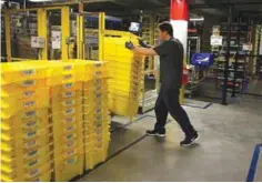  ??  ?? TRACY, California: This file photo taken on Jan 19, 2015 shows an Amazon.com worker moving a stack of containers at an Amazon fulfillmen­t center. — AFP