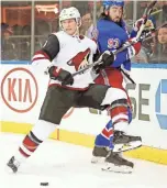  ??  ?? Coyotes defenseman Jakob Chychrun knocks Rangers center Mika Zibanejad (93) into the boards on Tuesday in New York.