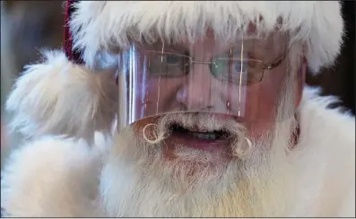  ?? (Ashley Landis/AP) ?? Santa Claus wears a face shield while visiting with children at Bass Pro Shop in Rancho Cucamonga, Calif., on Dec. 4. In this socially distant holiday season, Santa Claus is still coming to towns (and shopping malls) across America but with a few 2020 rules in effect.