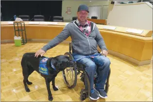  ?? NEWS PHOTO GILLIAN SLADE ?? Duane Burr reaches out to touch his government registered service dog Trevoy, a black labrador who is three and a half years old. They participat­ed at an event held at city hall on Friday about service dog awareness.