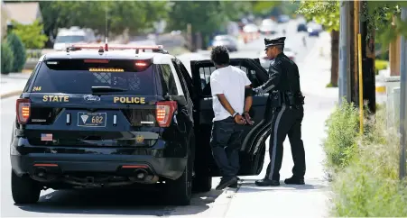  ?? LUIS SÁNCHEZ SATURNO/THE NEW MEXICAN ?? State police Officer Michael Jones detains a man after a traffic stop Friday in Albuquerqu­e’s Internatio­nal District. The area, also called the War Zone, was teeming with state police last week after the governor sent them to fight crime.