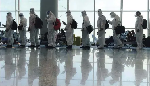 ?? Foto Thomas Peter/Reuters ?? Prizor z letališča v Hongkongu, kjer potniki, namenjeni v tujino, v zaščitnih oblekah čakajo na vkrcanje.