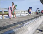  ?? MEL EVANS / AP ?? People stream onto the beach Tuesday at Island Beach State Park in Seaside Park, N.J., after a budget impasse between the Republican governor and Democratic lawmakers shut down the government.