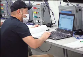  ??  ?? Jose Moreno of Tarkett works on his evening assignment of programmin­g an industrial automated computer to complete a timing function.