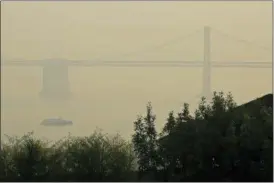  ?? ERIC RISBERG — THE ASSOCIATED PRESS ?? A ferryboat and the San Francisco-Oakland Bay Bridge are obscured due to smoke and haze from wildfires Monday in San Francisco.