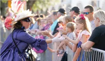  ?? GERALD HERBERT/AP ?? A costumed woman hands a trinket to a child Friday during a parade dubbed “Tardy Gras,” to compensate for a COVID-cancelled Mardi Gras celebratio­n, in Mobile, Alabama.