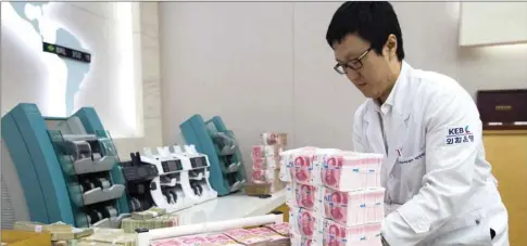  ??  ?? An employee arranges yuan banknotes at the Korea Exchange Bank headquarte­rs in Seoul (file). The yuan is under renewed pressure as China reacts to the trade war threat and the country’s monetary policy diverges from the US, where interest rates are on the rise.