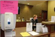  ??  ?? Amber Grove Place employee Thomas Pisani sits at the front desk surrounded by sanitizers and warning signs Wednesday in Chico.