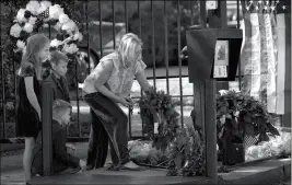  ?? ASSOCIATED PRESS ?? TIFFANY UTTERSON (RIGHT) AND HER CHILDREN (from left) Ella, 11, Ian, 10 and Owen, 8, place a wreath outside the gated community entrance to the home of George H.W. Bush on Sunday in Houston.