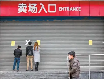  ?? Reuters-Yonhap ?? People stand at the entrance of a closed Lotte Mart store in Hangzhou, China, in March last year.