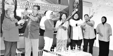  ??  ?? Fatimah (standing third left) getting assistance from Jenny (centre) with the party popper as part of a gimmick in launching of the programme. With her are John (second left), Fridah (first left) and others.